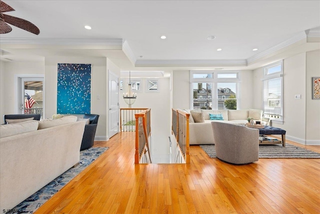 living room featuring crown molding, an inviting chandelier, a raised ceiling, and hardwood / wood-style floors