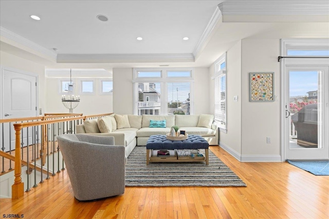 living room featuring crown molding, a tray ceiling, light hardwood / wood-style floors, and a notable chandelier