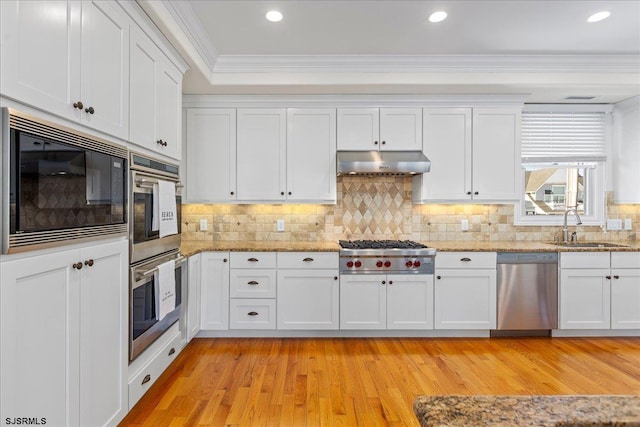 kitchen with sink, stainless steel appliances, ornamental molding, white cabinets, and light wood-type flooring