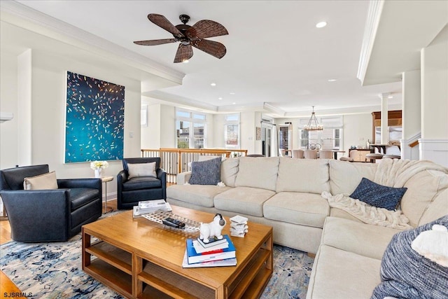 living room featuring crown molding, ceiling fan with notable chandelier, light hardwood / wood-style floors, and decorative columns