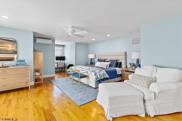 bedroom with ceiling fan, a wall unit AC, and light hardwood / wood-style flooring