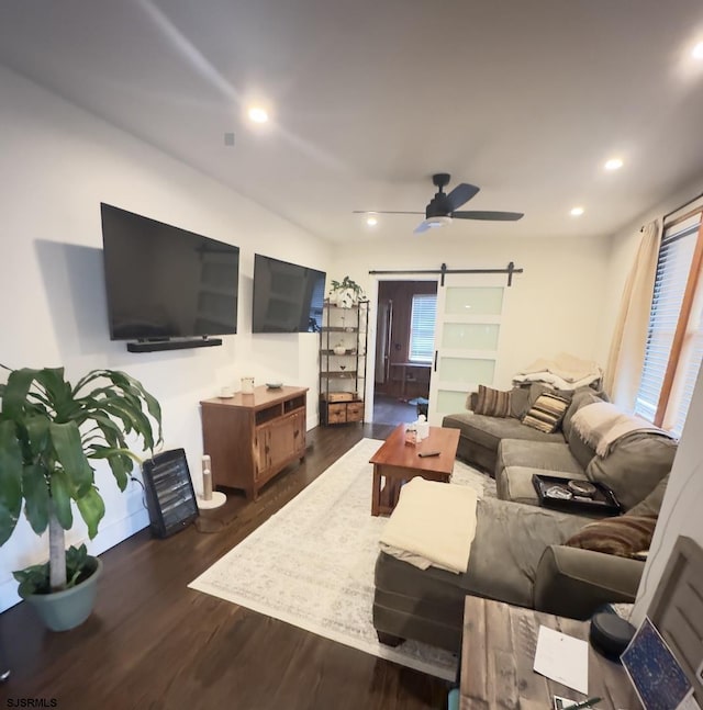 living room with a barn door, dark hardwood / wood-style floors, and ceiling fan