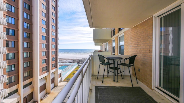 balcony with a water view and a view of the beach