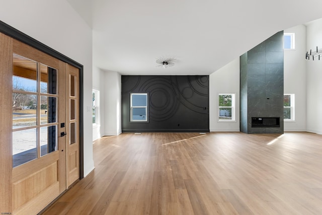 unfurnished living room with a premium fireplace, light hardwood / wood-style floors, and a high ceiling