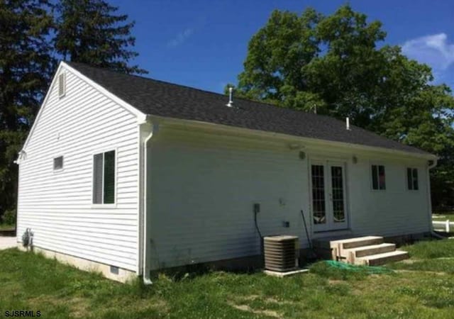 rear view of property with cooling unit, a lawn, and french doors