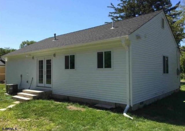 rear view of house with central AC and a lawn