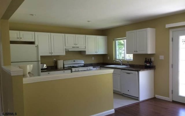 kitchen with sink, white cabinetry, wood-type flooring, kitchen peninsula, and white appliances