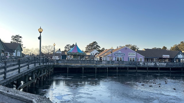 view of community with a pier, a water view, and uncovered parking