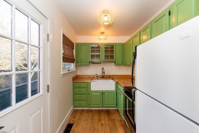 kitchen featuring electric stove, sink, butcher block countertops, white refrigerator, and green cabinetry