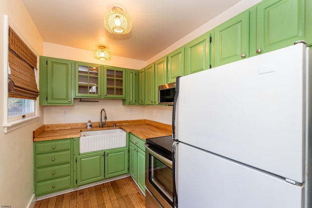 kitchen with wood counters, sink, light wood-type flooring, appliances with stainless steel finishes, and green cabinets