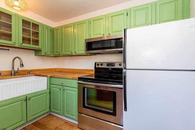 kitchen with sink, light hardwood / wood-style flooring, stainless steel appliances, and green cabinets