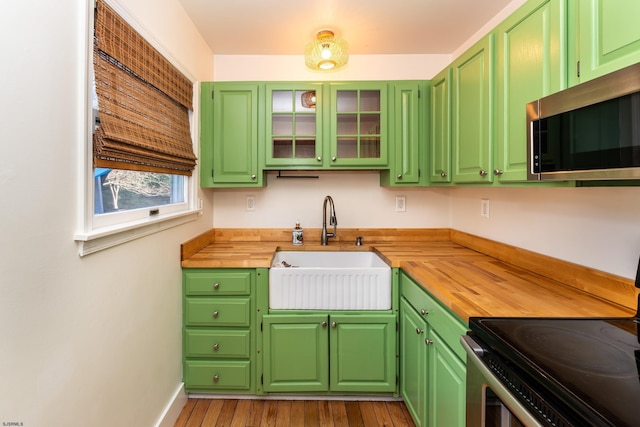 kitchen featuring wood counters, stainless steel appliances, sink, and green cabinetry