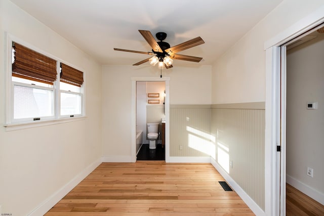 unfurnished bedroom with ceiling fan, connected bathroom, and light wood-type flooring