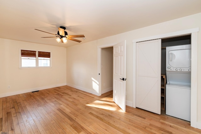 unfurnished bedroom with stacked washer / drying machine, ceiling fan, and light hardwood / wood-style flooring