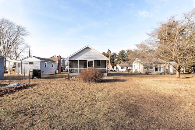 rear view of property featuring a sunroom and a lawn