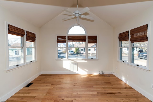 unfurnished room featuring a wealth of natural light, light hardwood / wood-style floors, ceiling fan, and vaulted ceiling