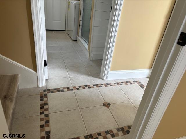 hallway featuring light tile patterned floors and washer / clothes dryer