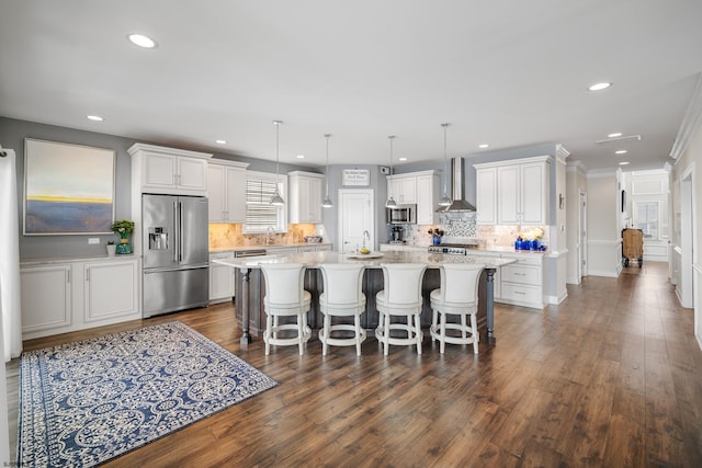 kitchen featuring white cabinetry, pendant lighting, wall chimney exhaust hood, and appliances with stainless steel finishes