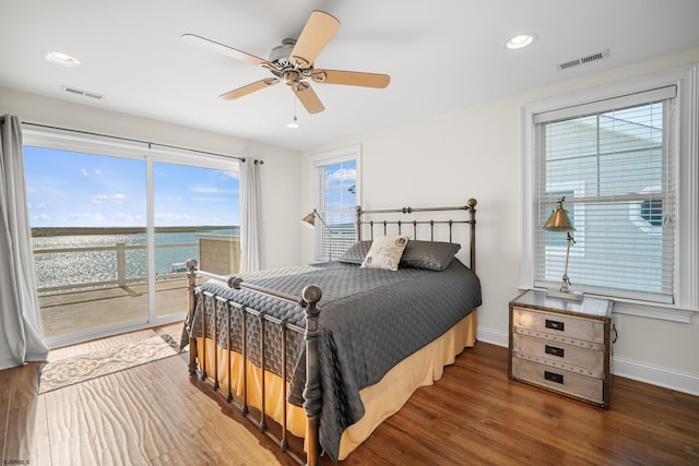 bedroom featuring a water view, dark hardwood / wood-style floors, access to exterior, and ceiling fan