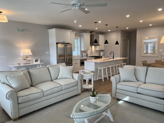 living room with sink, light hardwood / wood-style floors, and ceiling fan