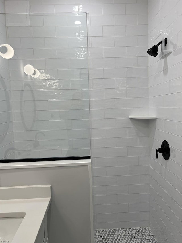 bathroom featuring a tile shower and vanity