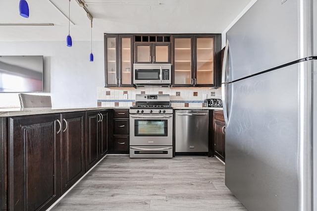 kitchen featuring hanging light fixtures, decorative backsplash, light hardwood / wood-style floors, and appliances with stainless steel finishes