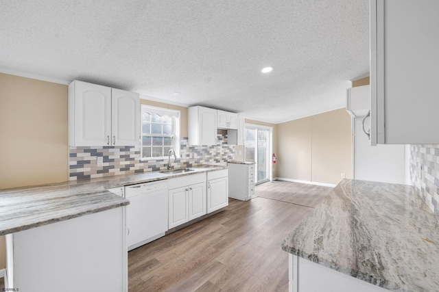 kitchen with sink, light hardwood / wood-style flooring, dishwasher, light stone countertops, and white cabinets