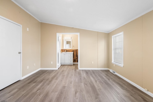 empty room with crown molding, lofted ceiling, and light hardwood / wood-style flooring