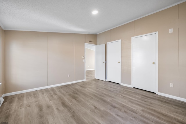 unfurnished bedroom with crown molding, a textured ceiling, and light hardwood / wood-style floors