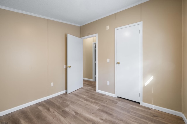 unfurnished bedroom featuring crown molding and light hardwood / wood-style floors