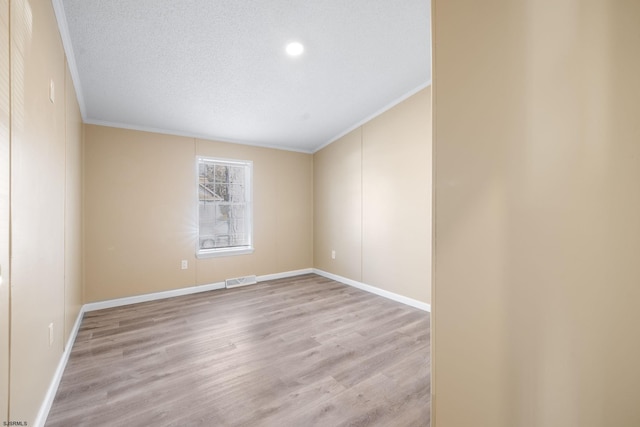 empty room with crown molding, light hardwood / wood-style flooring, and a textured ceiling