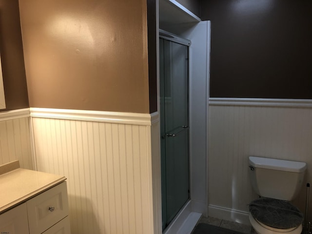 bathroom featuring vanity, toilet, and a shower with shower door