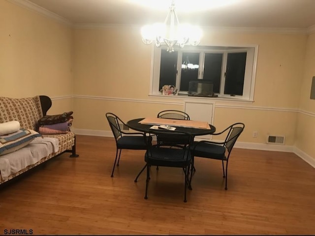 dining area with hardwood / wood-style flooring, crown molding, and a notable chandelier