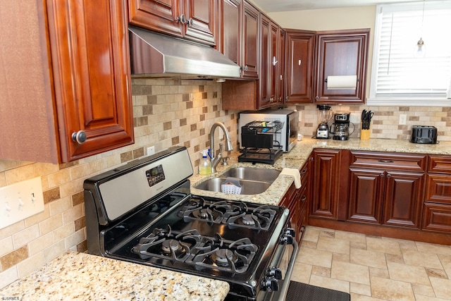 kitchen with stainless steel gas range, sink, light stone countertops, and backsplash