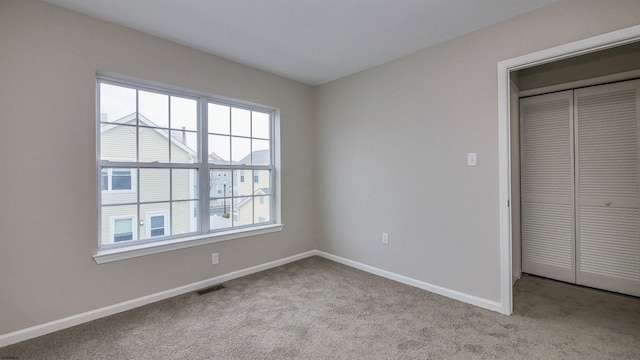 unfurnished bedroom with light carpet and a closet