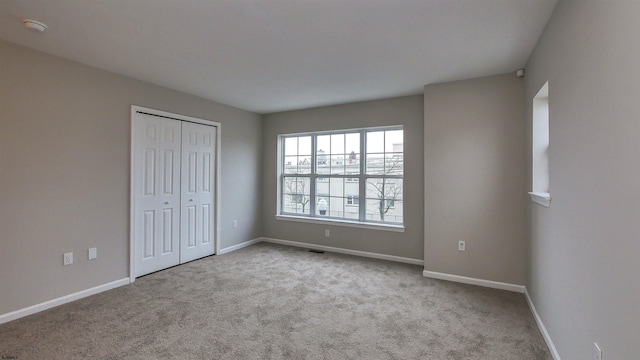 unfurnished bedroom with a closet and light carpet