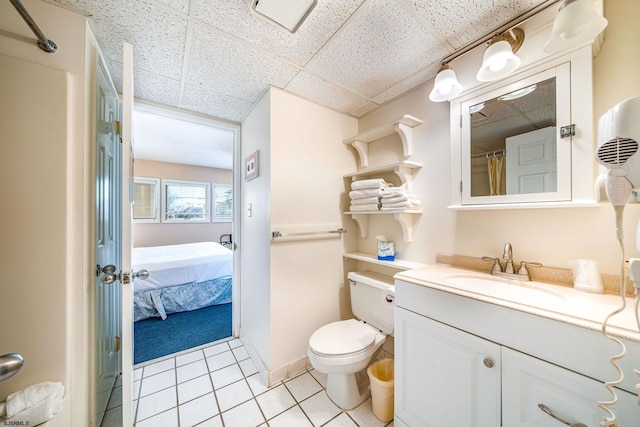 bathroom featuring tile patterned flooring, vanity, a paneled ceiling, and toilet