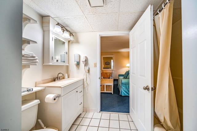 bathroom with vanity, tile patterned floors, toilet, and a drop ceiling