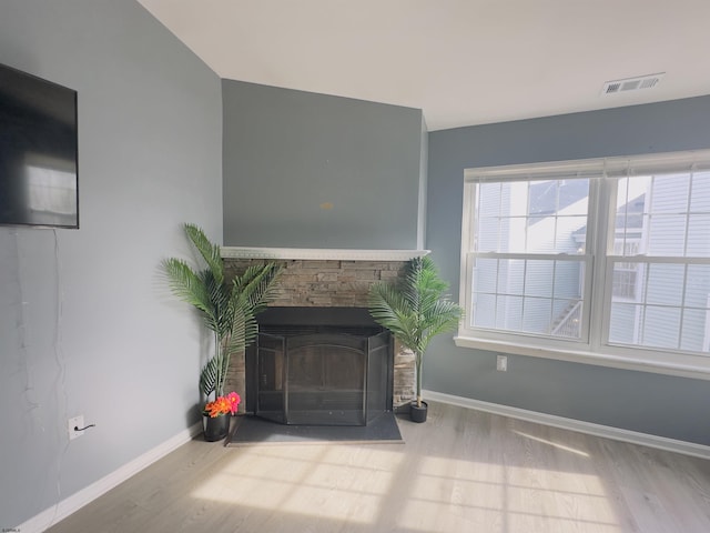 unfurnished living room featuring a stone fireplace and light wood-type flooring