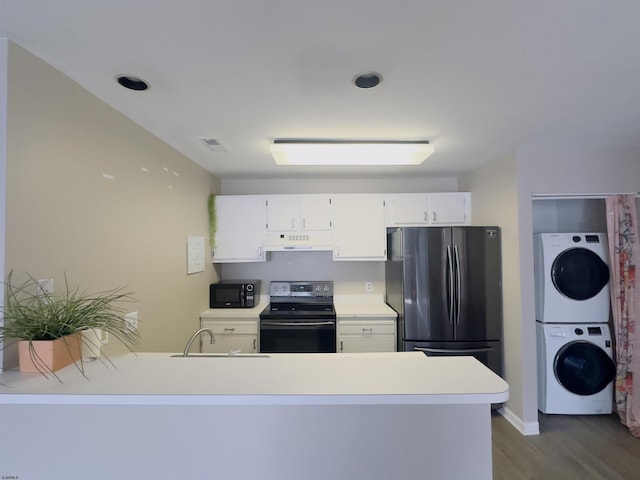 kitchen featuring sink, stainless steel range with electric stovetop, fridge, stacked washer / dryer, and white cabinets