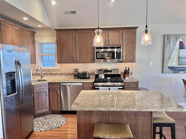 kitchen featuring vaulted ceiling, appliances with stainless steel finishes, sink, and pendant lighting