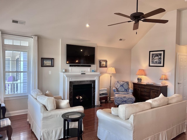 living room featuring a high end fireplace, vaulted ceiling, dark hardwood / wood-style floors, and ceiling fan