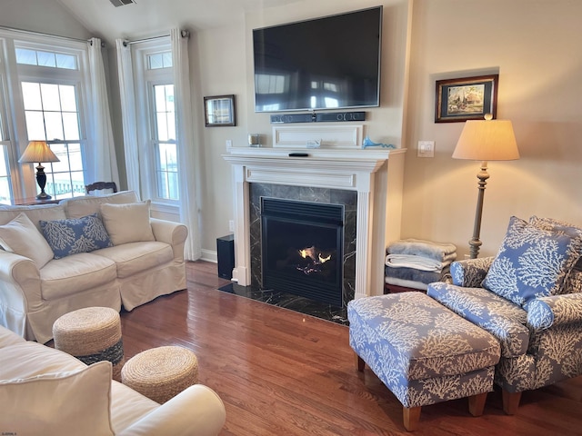 living room featuring vaulted ceiling, dark wood-type flooring, and a high end fireplace