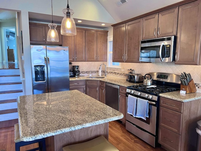 kitchen featuring a kitchen bar, sink, light stone counters, a center island, and stainless steel appliances