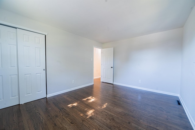 unfurnished bedroom featuring dark wood-type flooring and a closet