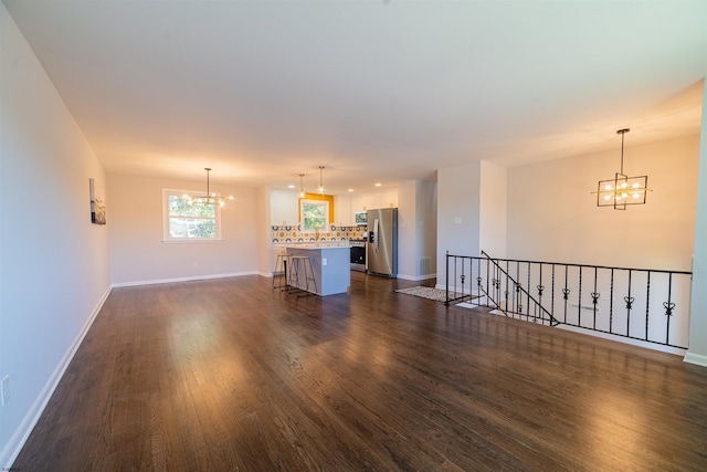 unfurnished living room featuring dark hardwood / wood-style floors and a notable chandelier