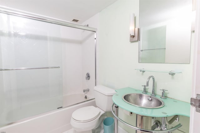 full bathroom with sink, shower / bath combination with glass door, and toilet