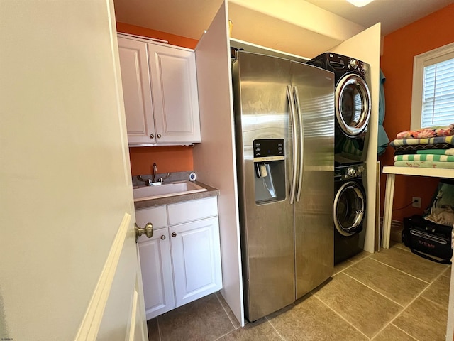 laundry room featuring stacked washer and dryer, sink, light tile patterned floors, and cabinets