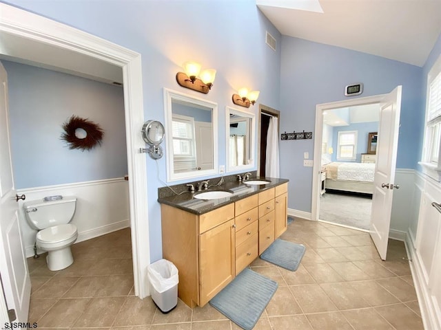 bathroom featuring lofted ceiling, vanity, tile patterned floors, and toilet