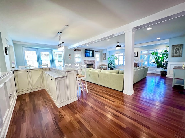 kitchen with dark hardwood / wood-style floors, a fireplace, a breakfast bar, and light stone counters